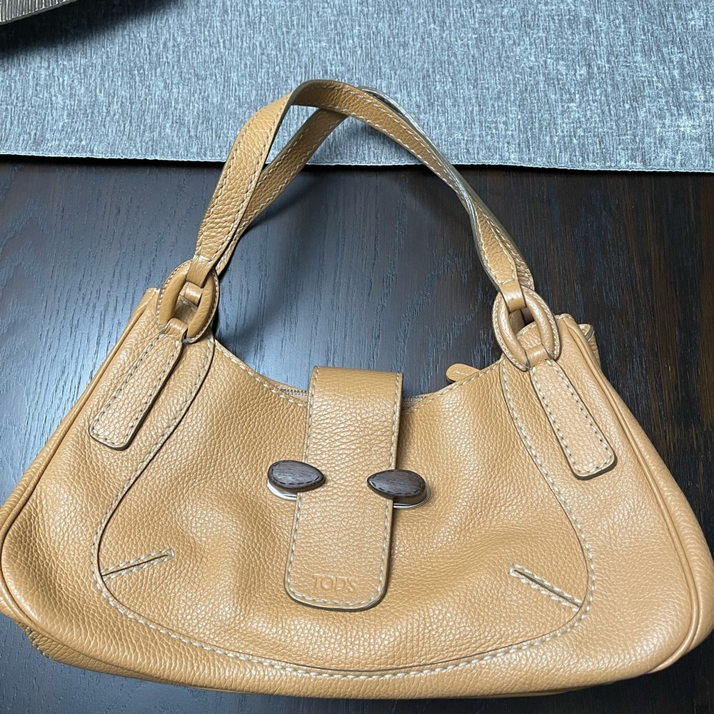 Tod’s Pebble Leather Handbag with wood detail.  It’s a beige/orange color.